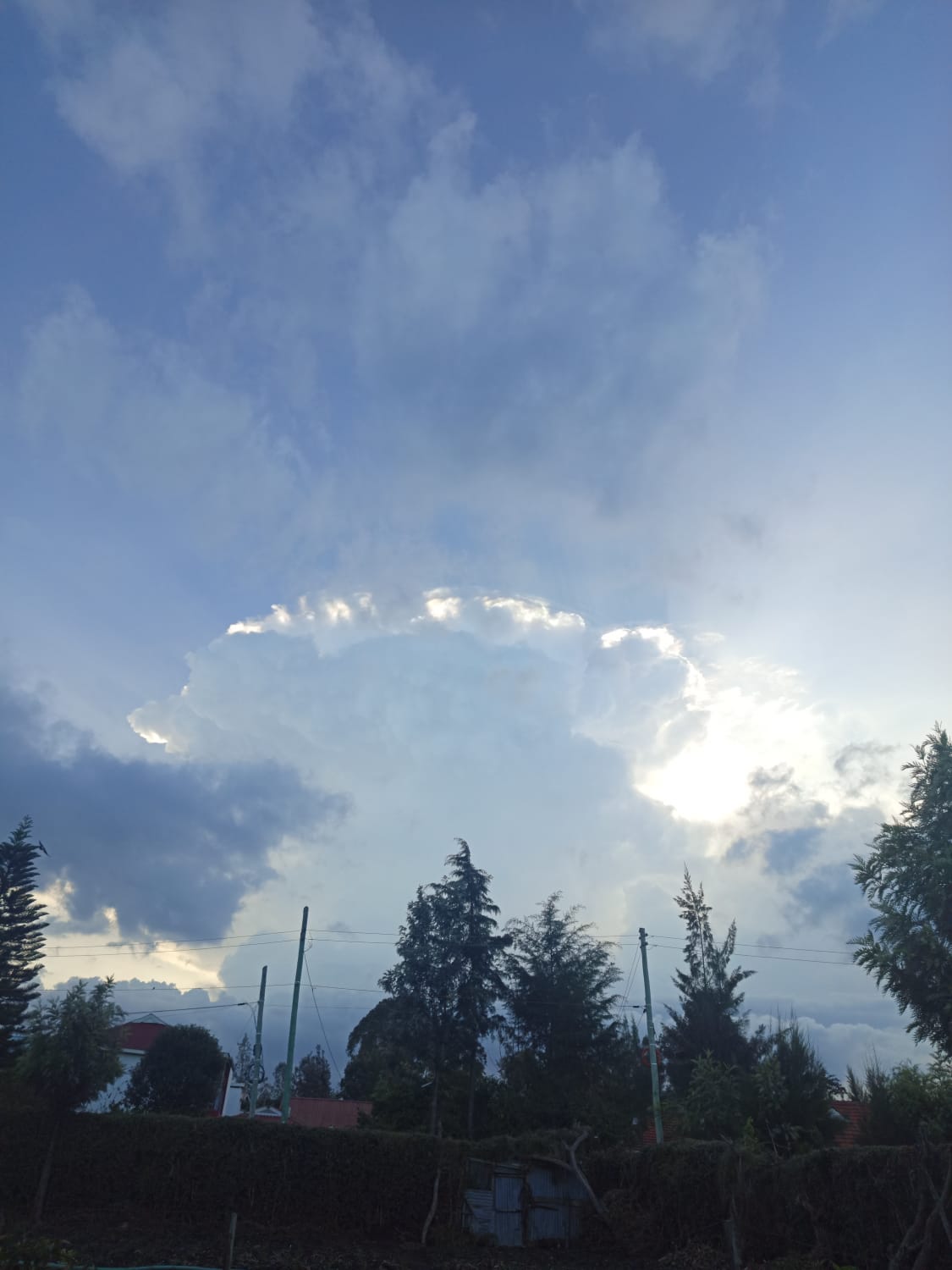 A beautiful 'silver lining' effect where the sun is hidden behind a large, billowing cumulus cloud, illuminating its edges with bright white light.